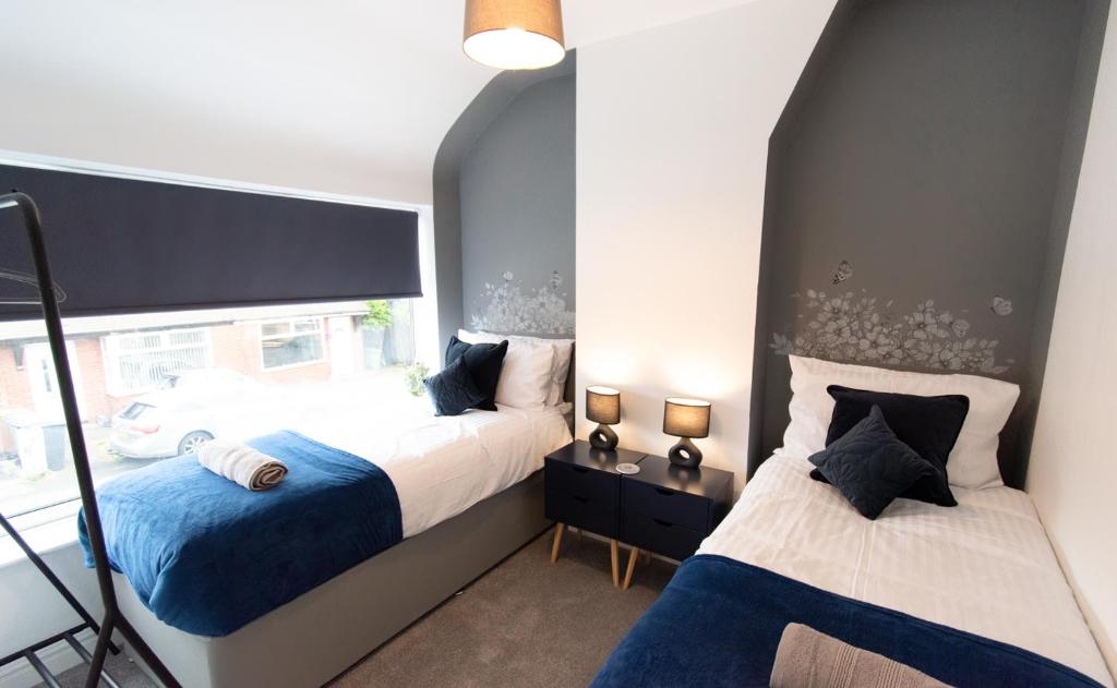 曼彻斯特Ideal Lodgings In Audenshaw的一间卧室设有两张床和窗户。