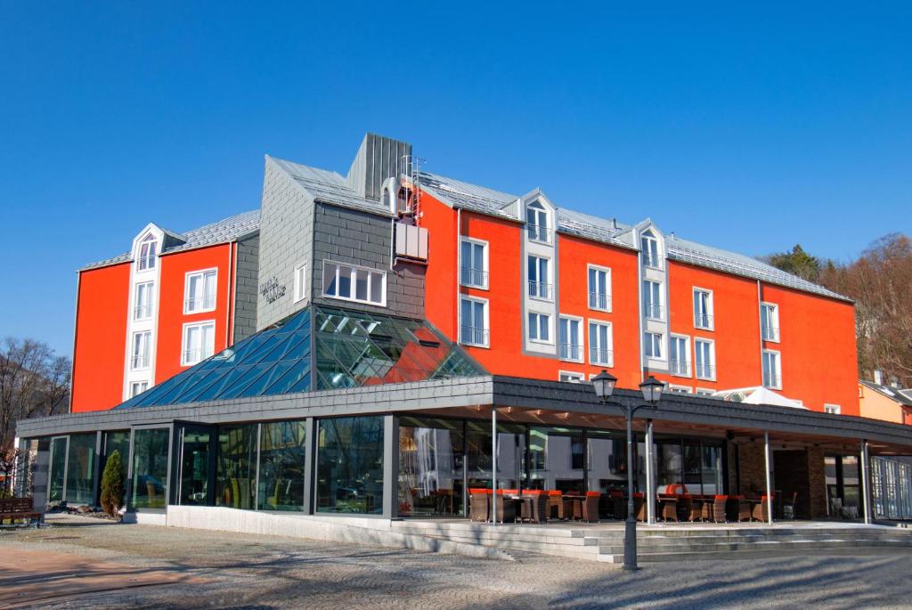 伊尔梅瑙Hotel Tanne Ilmenau的一座大型橙色建筑,前面设有玻璃窗