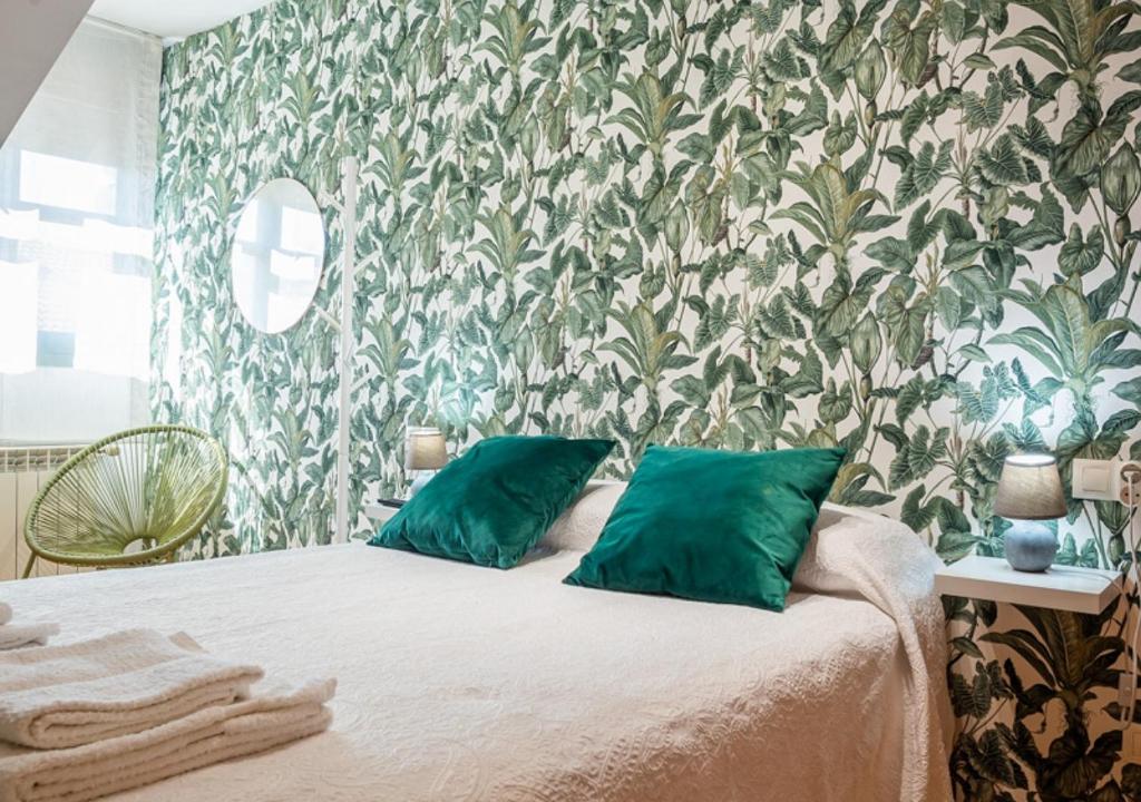 坎加斯-德奥尼斯Apartamento Irene céntrico con Wifi y parking coche tamaño medio Cangas de Onís的一间卧室配有一张带绿色枕头的床和壁纸