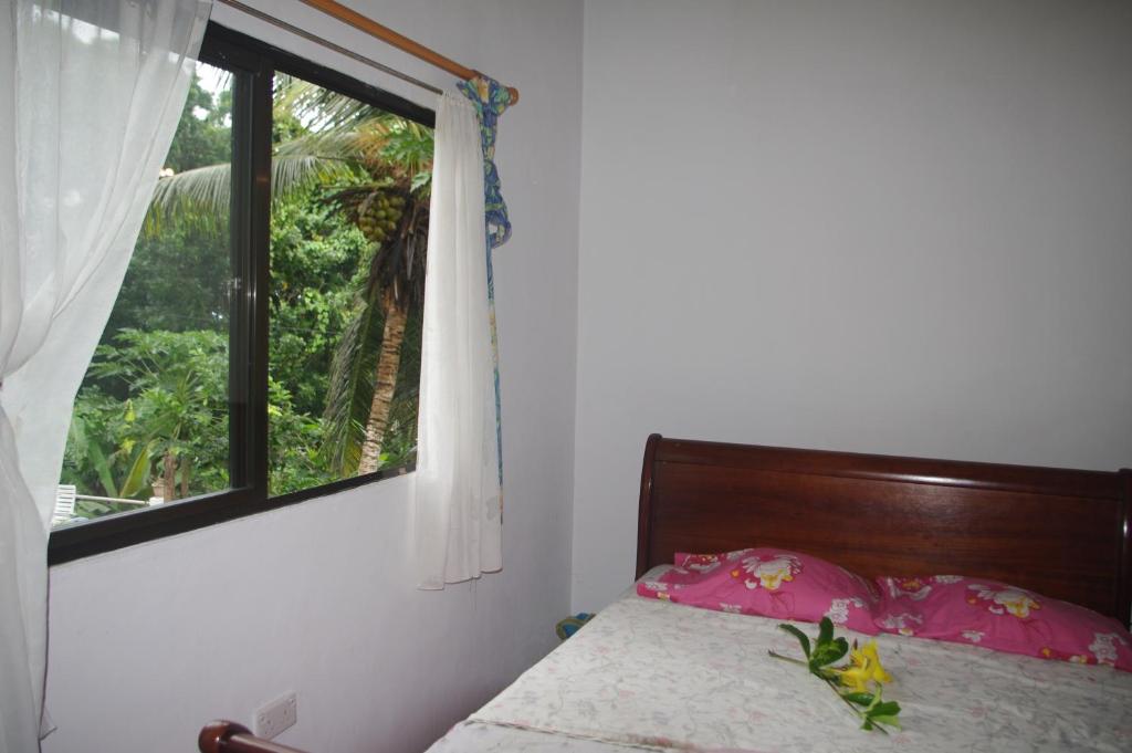 马埃岛木瓜别墅的一间卧室配有一张带窗户的床和床罩