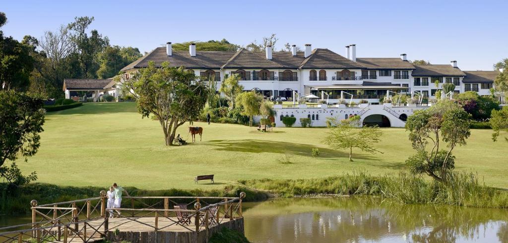 纳纽基费尔蒙特山肯尼亚野生动物园俱乐部酒店的池塘旁高尔夫球场上的大型房子