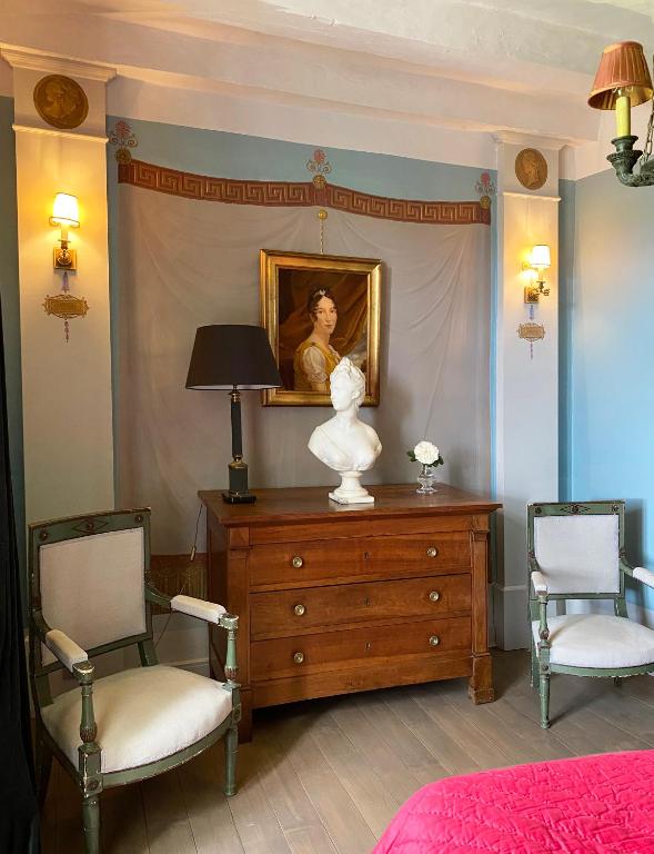 FreignéManoir de Ghaisne的一间卧室配有带绘画的梳妆台和两把椅子
