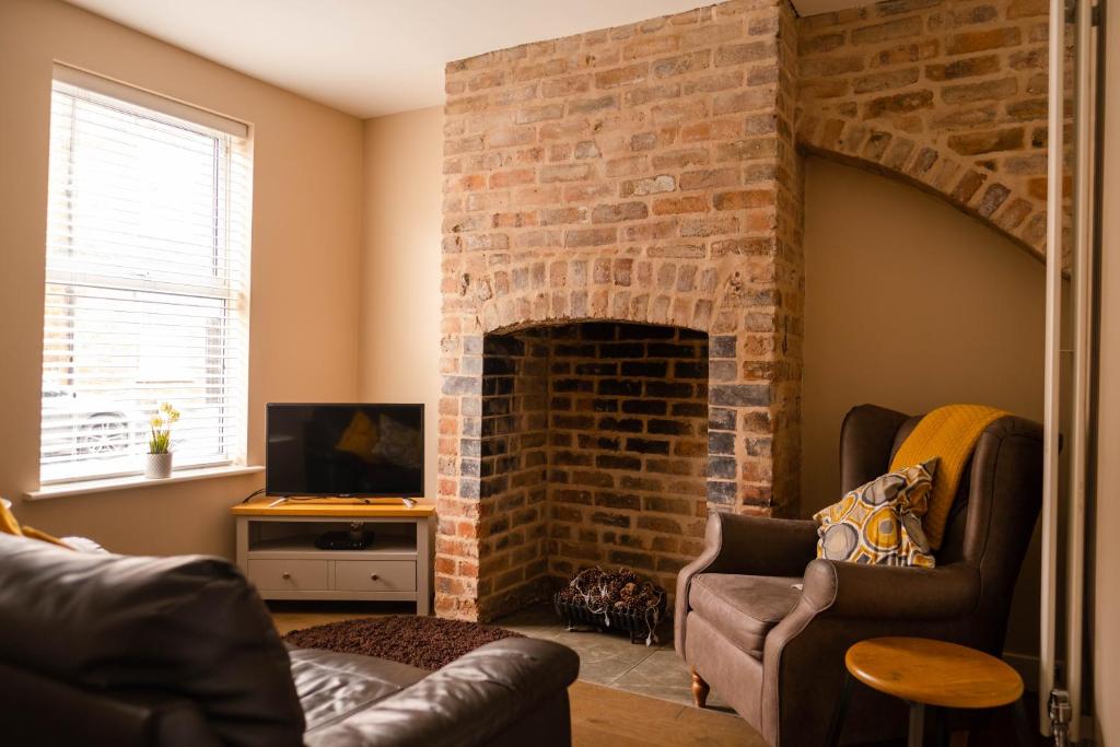 什鲁斯伯里Rose Cottage的客厅设有砖砌壁炉及两把椅子