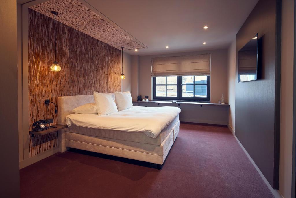 维格尔The Yard hotel Noordkade的一间卧室设有一张大床和一个窗户。