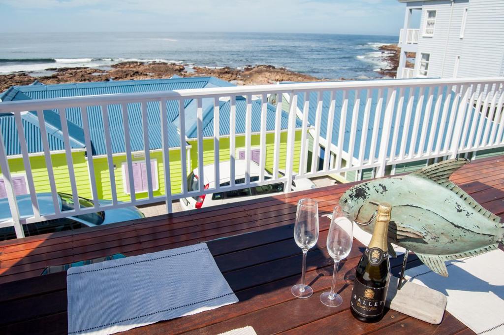 莫塞尔湾Barefoot Lodge, Mossel Bay的阳台上的桌子上放着两杯酒和一条鱼