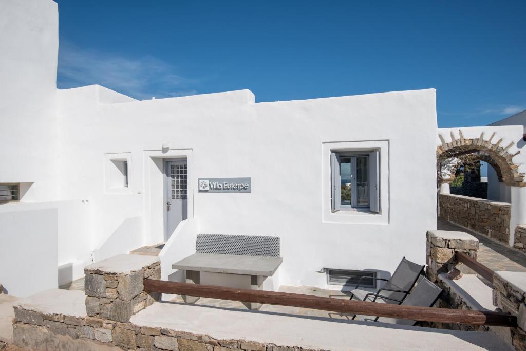 安倍拉斯Seaview Villa Euterpe的白色的房子,在庭院配有桌椅