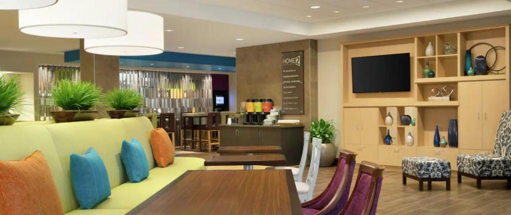 彭萨科拉Home2 Suites By Hilton Pensacola Airport Medical Center的一间带桌椅和电视的餐厅