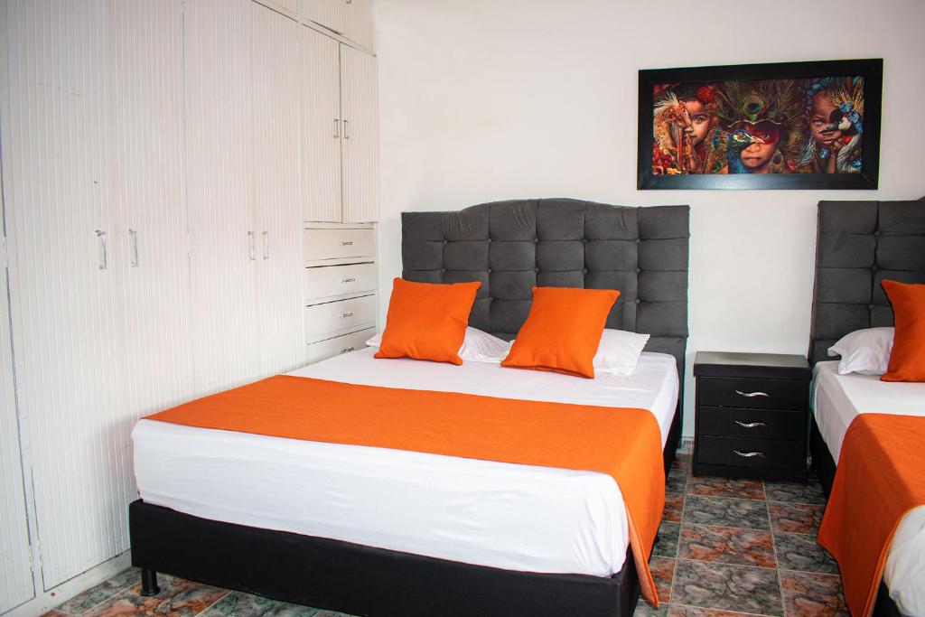 波哥大Hotel BogoSuba 127的一间卧室配有两张带橙色枕头的床