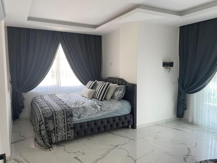 马赫姆拉Fully furnished 1+1 apartment in luxury complex Heaven Hills的一间卧室配有一张带蓝色窗帘的床和一扇窗户