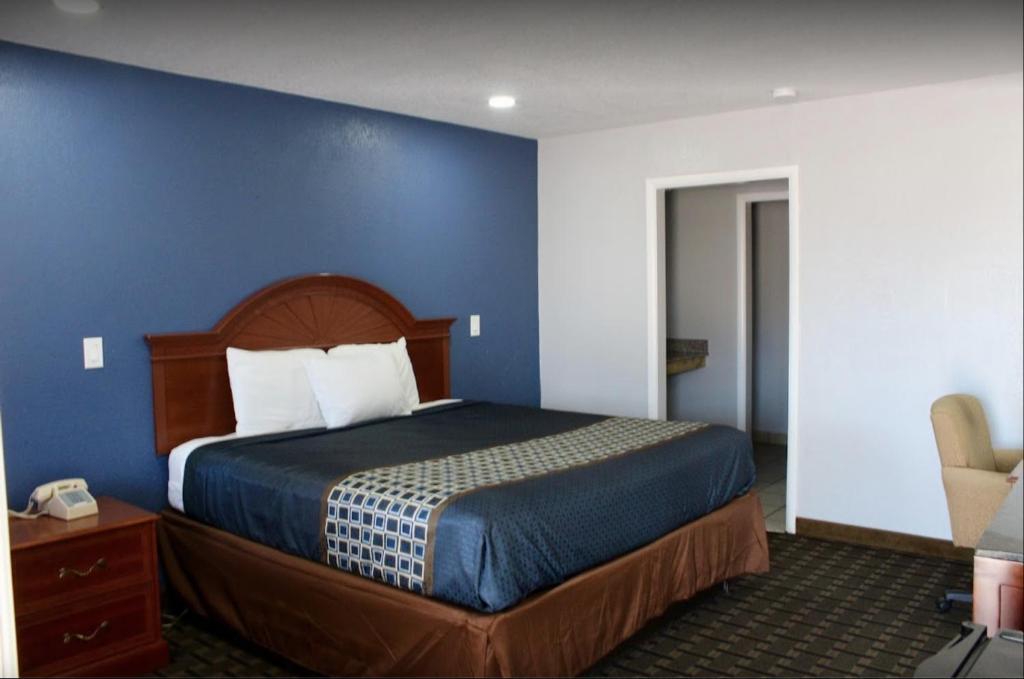 艾达Economy Inn的一间卧室设有一张蓝色墙壁的大床