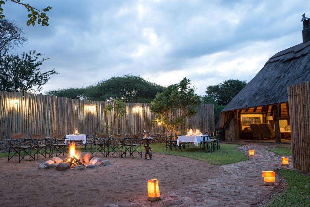 Manyoni Private Game ReserveRhino River Lodge的一个带火坑、桌子和茅草屋顶的庭院