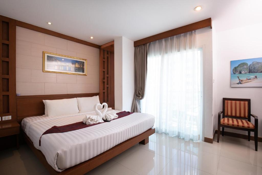 芭东海滩The Patong Center Hotel的一间卧室配有一张带窗户和椅子的床
