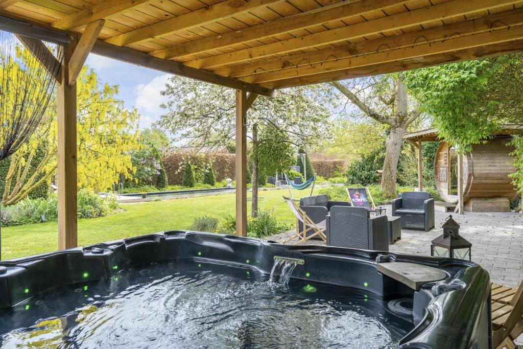 马斯梅赫伦Maas&Mechelen B&B Massage & Wellness的后院的热水浴池,带凉棚