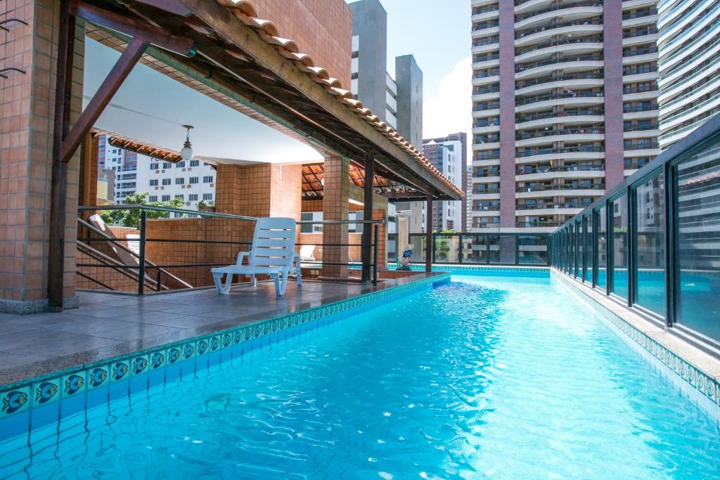 福塔莱萨Ideal Praia Hotel的一座游泳池,旁边是一座建筑,配有椅子