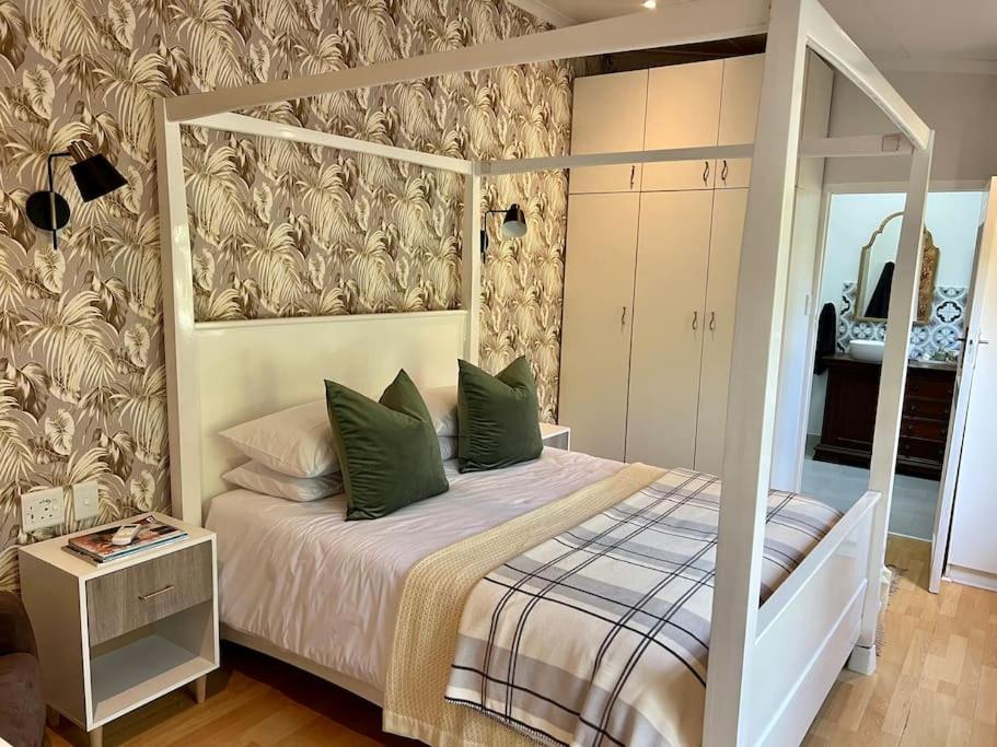 德班Stirling Cottage的一间卧室配有一张带绿色枕头的天蓬床