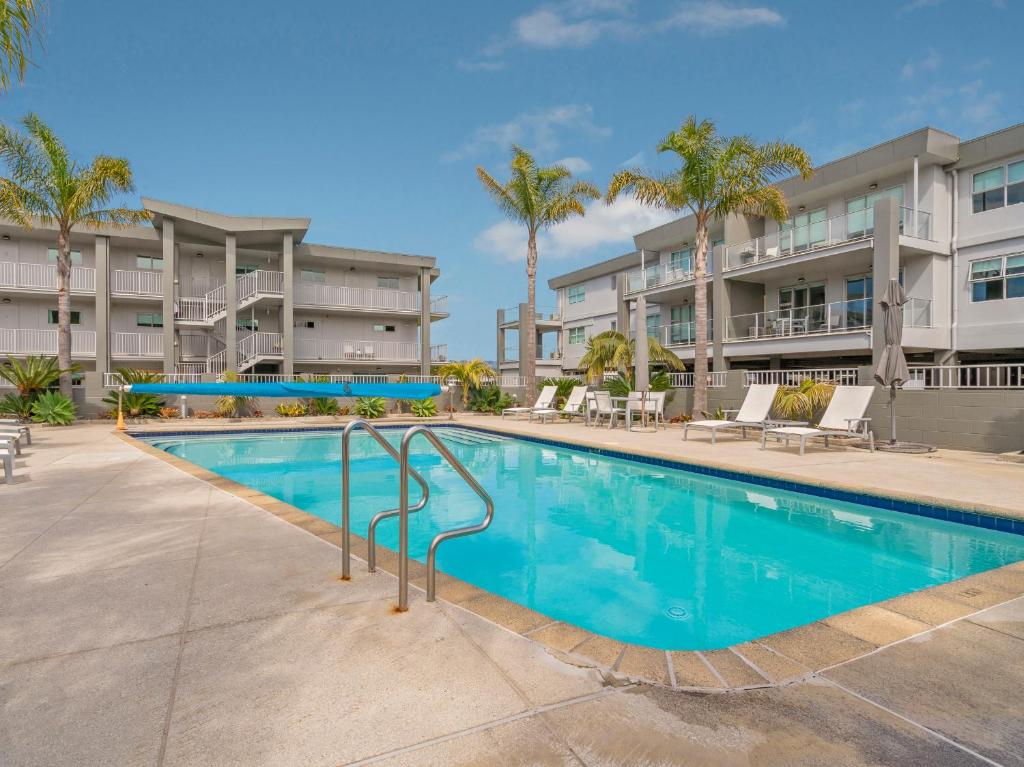 怀蒂昂格Marinaview - Whitianga Holiday Apartment的棕榈树公寓大楼内的游泳池