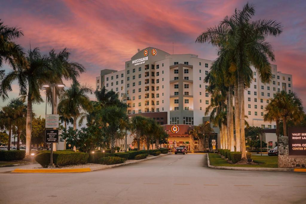 迈阿密Miccosukee Casino & Resort的一条白色的大建筑,在街上种有棕榈树