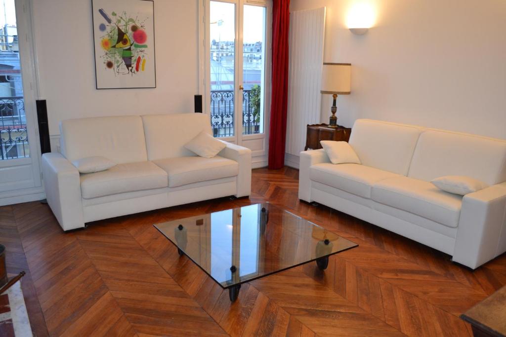 巴黎红磨坊二号公寓的客厅配有2张白色沙发和玻璃桌
