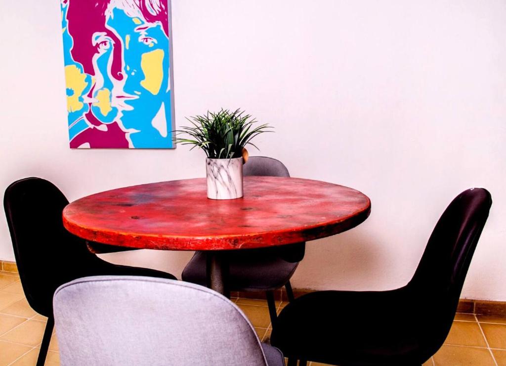 拉巴斯Villa Esterito的一张红色桌子,四周摆放着椅子,上面有植物