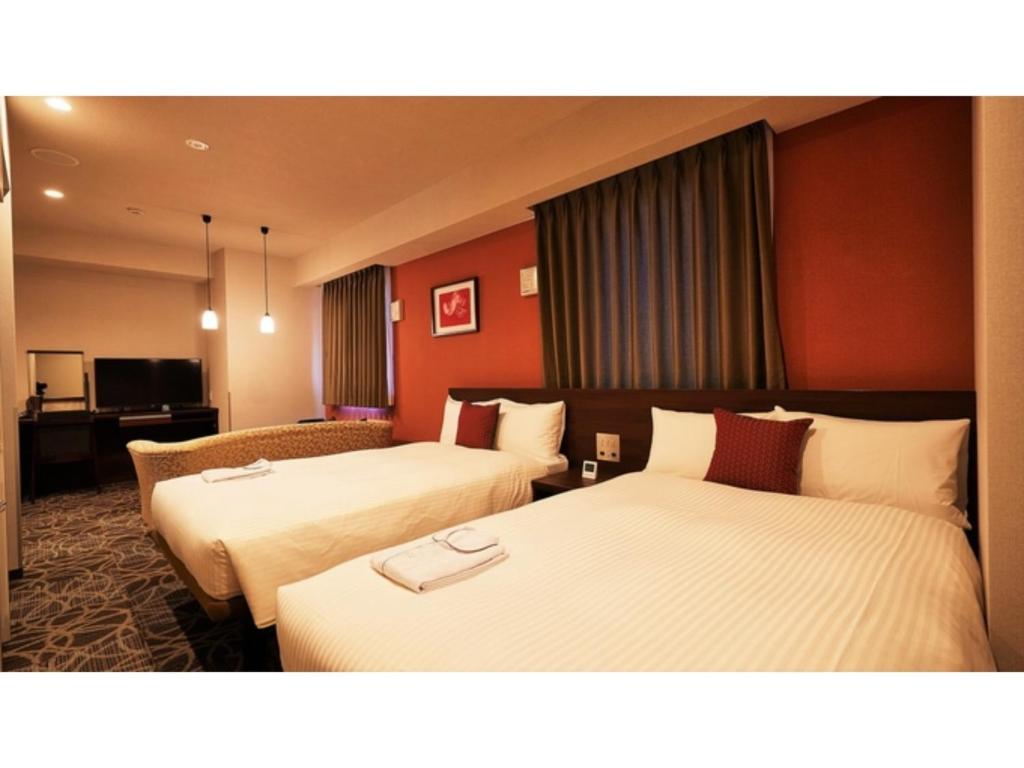 那霸Y's Inn Naha Oroku Ekimae - Vacation STAY 25859v的红色墙壁的酒店客房内的两张床
