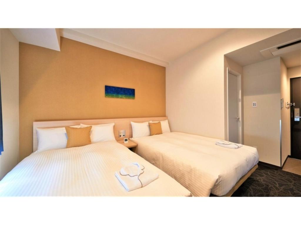 那霸Y's Inn Naha Oroku Ekimae - Vacation STAY 25852v的酒店客房,配有两张带毛巾的床