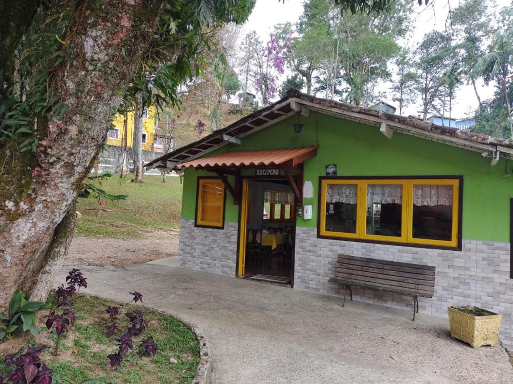 佩尼多Pousada Bela Vista的一座绿色建筑,前面设有长凳