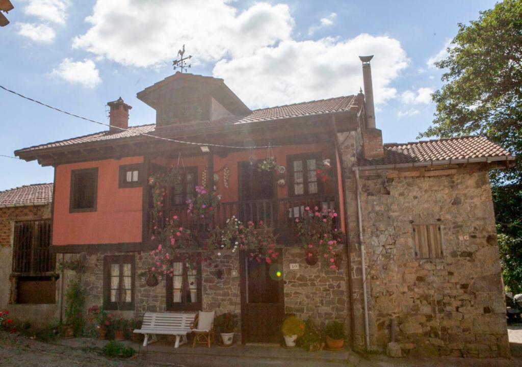 波拉-德拉维亚纳Casa Rural La Aldea的一座古老的砖房,前面有鲜花