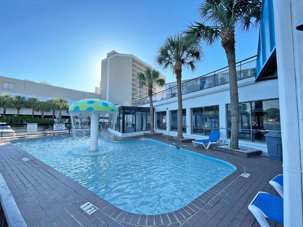 默特尔比奇Polynesian Oceanfront Hotel的一座大楼中央的带遮阳伞的游泳池