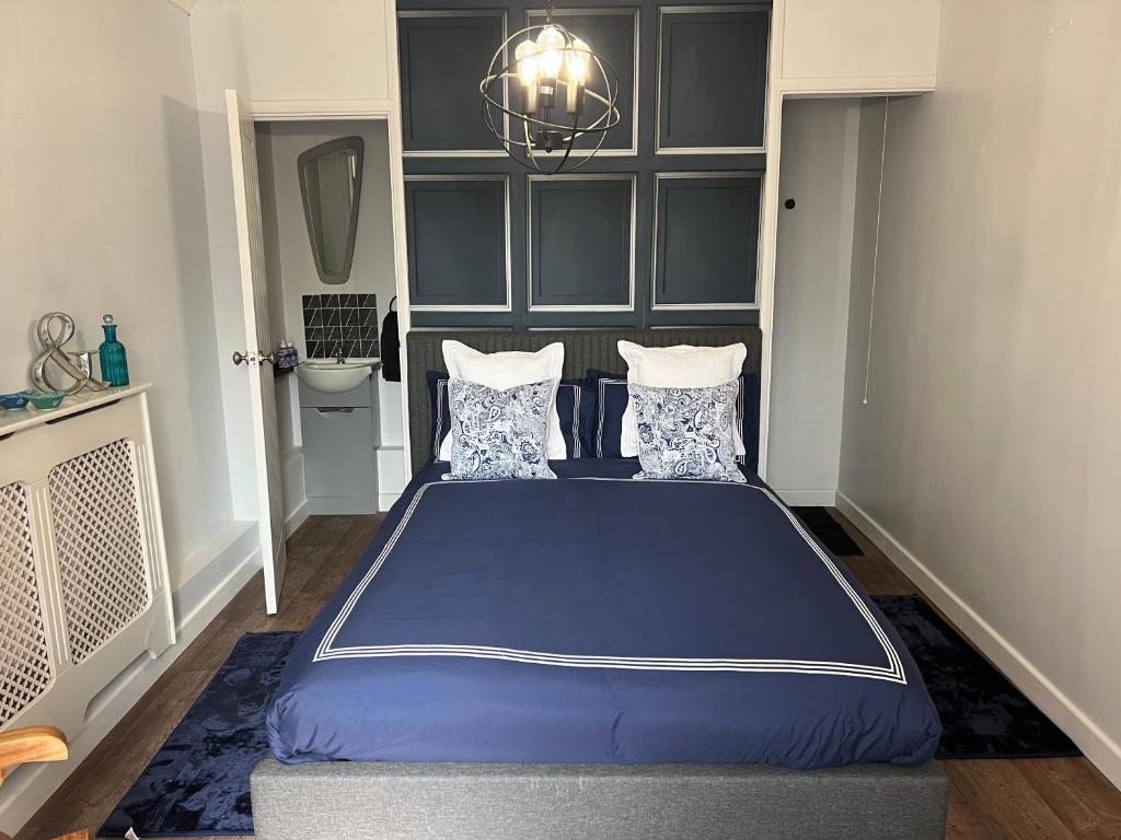 格拉斯顿伯里Glastonbury Hideaway的一间卧室配有蓝色的床和吊灯。