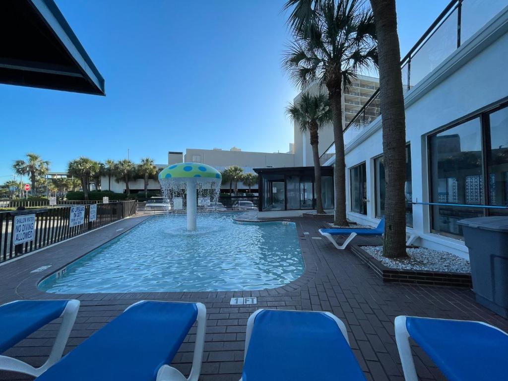 默特尔比奇Polynesian Oceanfront Hotel的一个带遮阳伞和蓝色椅子的游泳池