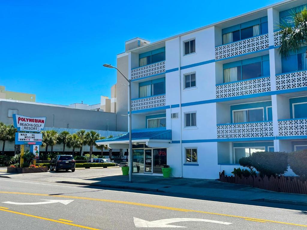 默特尔比奇Polynesian Oceanfront Hotel的前面有一辆汽车停放的白色建筑