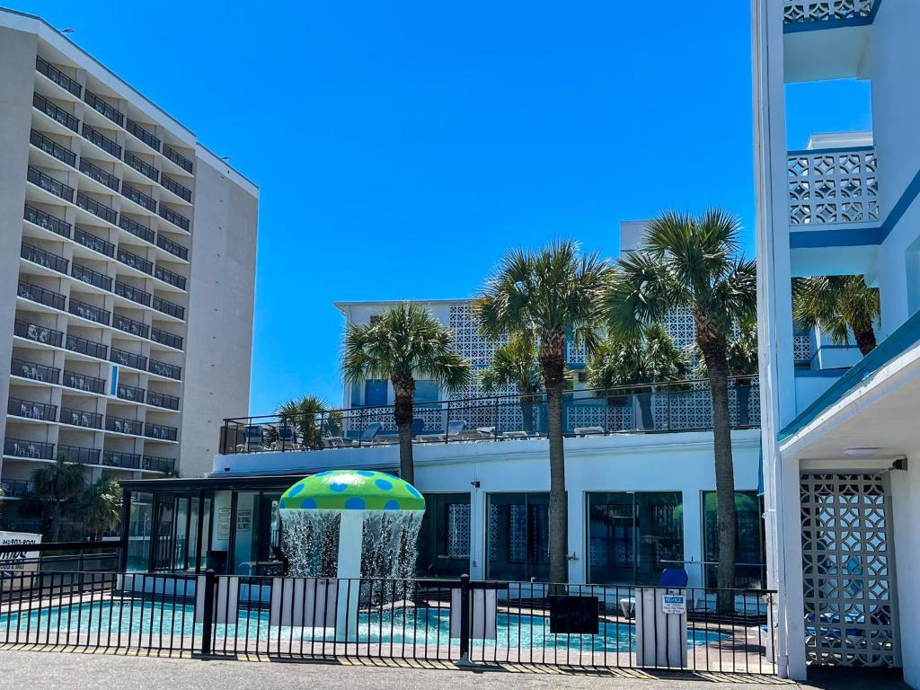 默特尔比奇Polynesian Oceanfront Hotel的一座棕榈树和遮阳伞的建筑