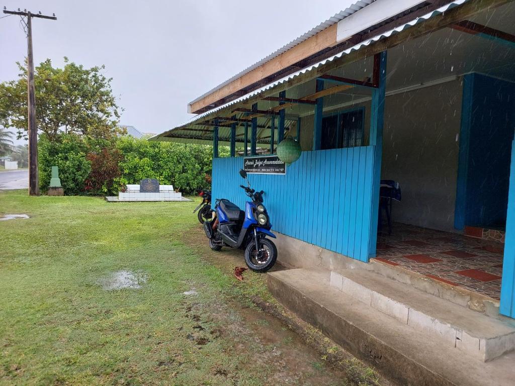 AmuriAitutaki Budget Accommodation的停在蓝色建筑外的摩托车