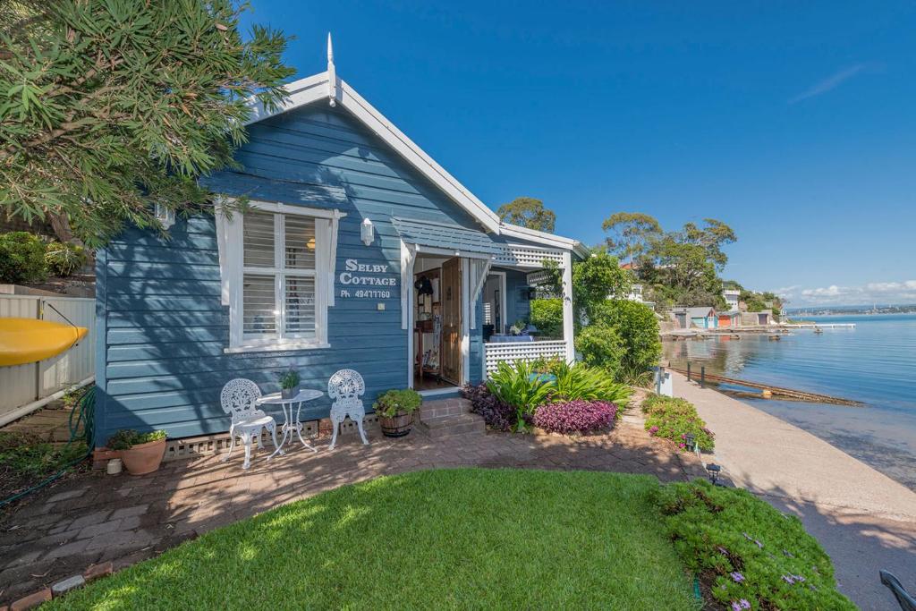 Marks PointSelby Cottage - Intimate Waterfront Getaway的蓝色的房子,配有两把椅子和庭院
