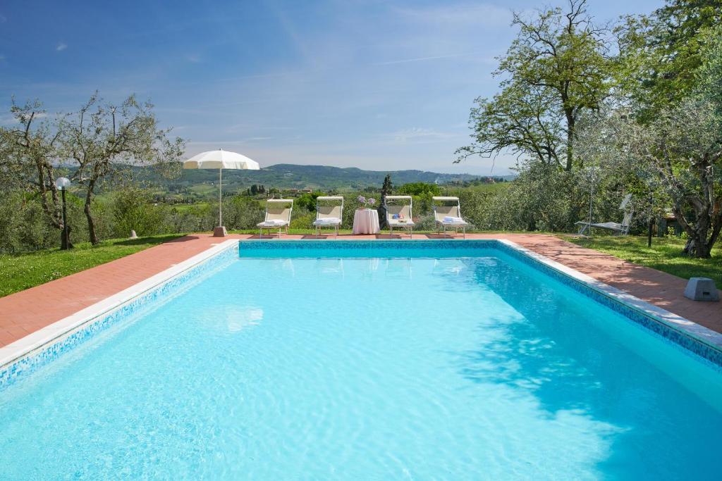 蒙泰斯佩尔托利Villa I Leoni的一个带椅子和树木的大型蓝色游泳池