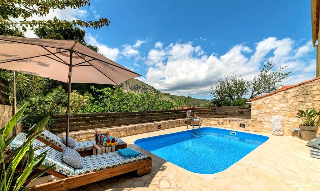 MouríonApple Villas的游泳池旁设有遮阳伞和椅子的游泳池