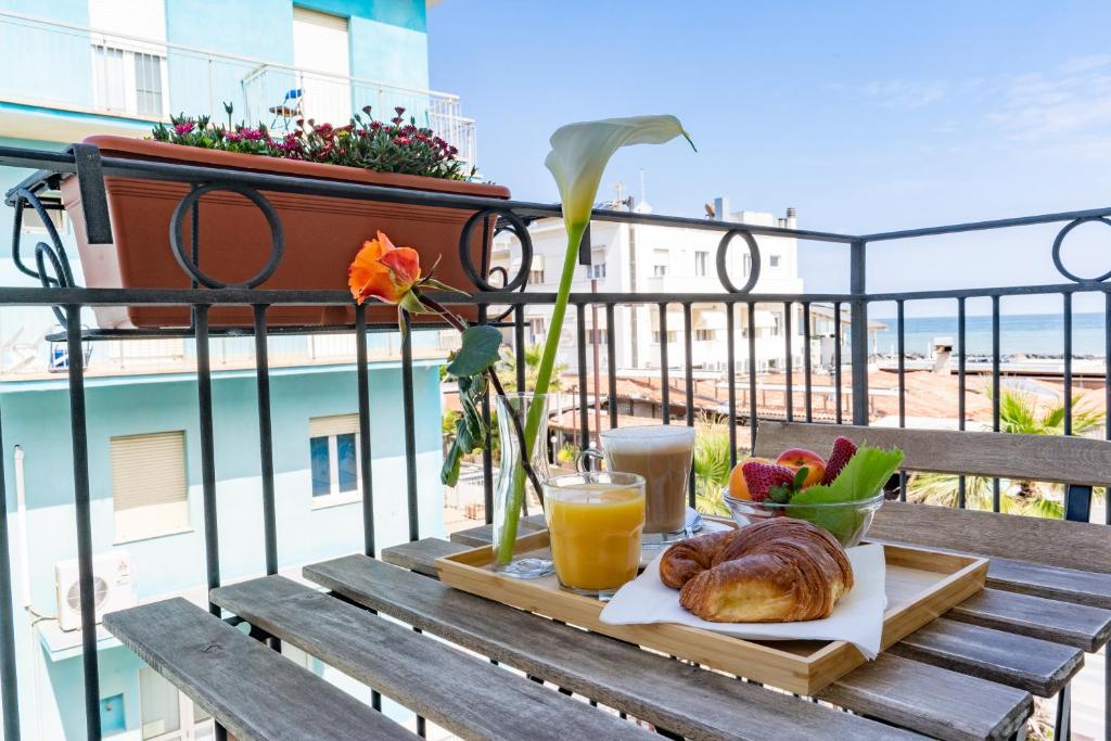 里米尼Hotel Greta B&B的阳台上的桌子上放着面包和果汁