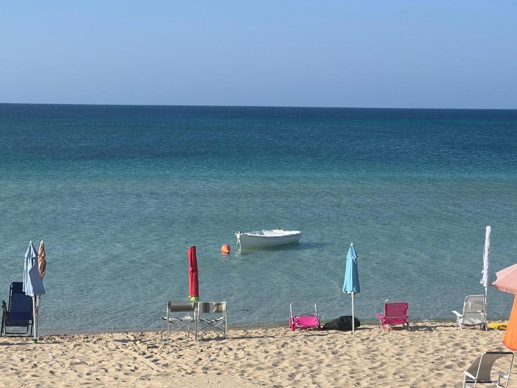 贝瓦尼亚圣彼得A due passi sul mare的海滩上,沙滩上摆放着椅子,水中还坐着一条船