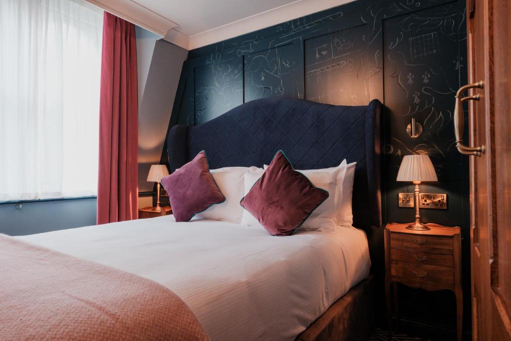 伦敦富勒圣殿酒店的一间卧室配有一张带紫色枕头的大床