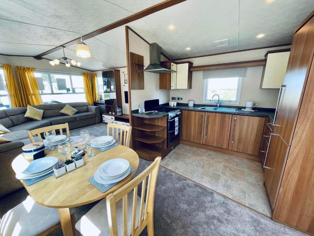 SouthminsterSuperb Caravan At Steeple Bay Holiday Park In Essex, Sleeps 6 Ref 36081d的厨房以及带木桌和椅子的客厅。