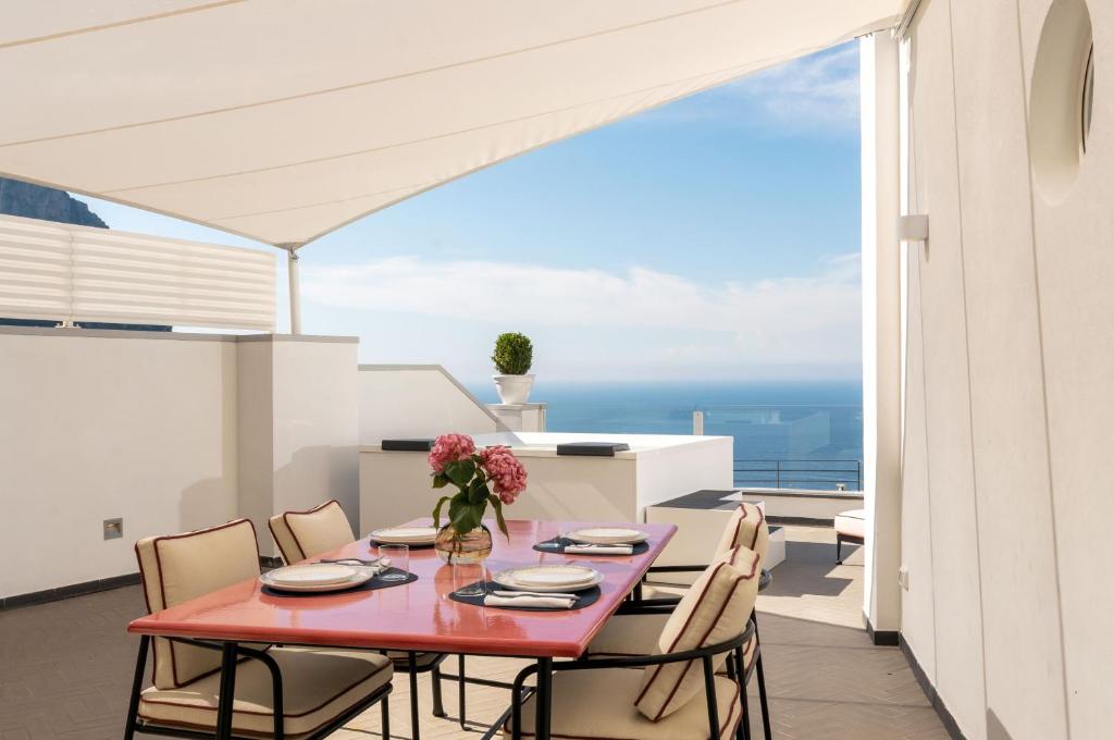卡普里Palazzo M Capri的阳台的用餐室配有红色的桌子和椅子