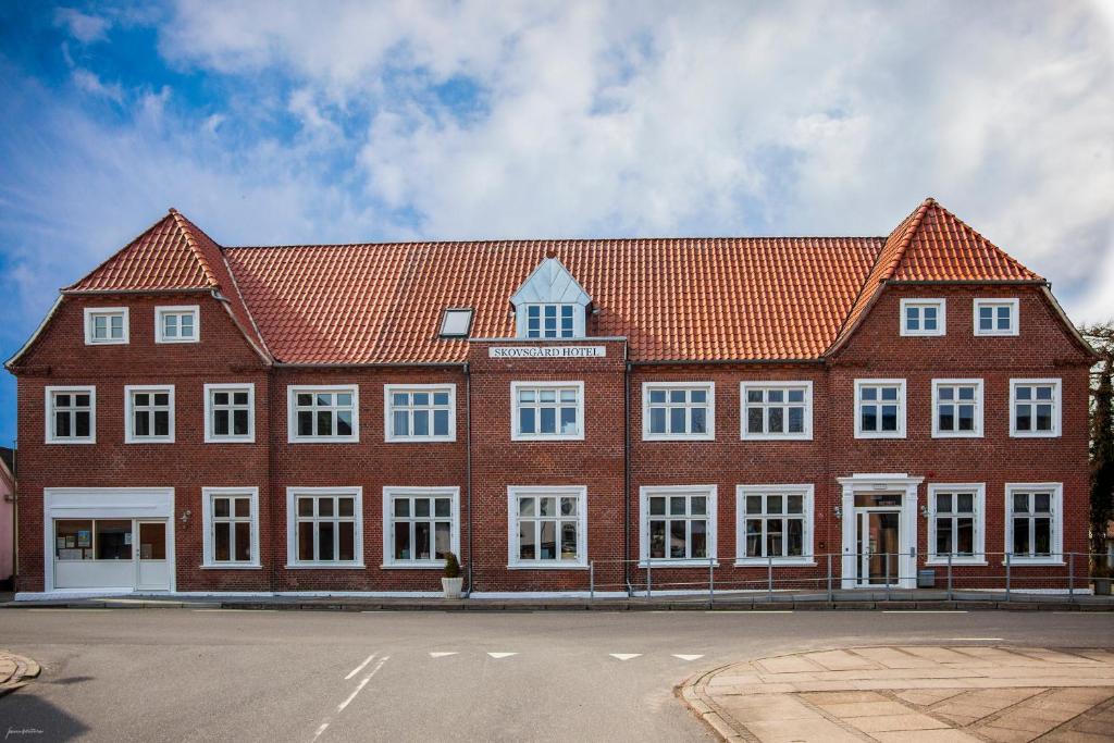 布罗斯特Skovsgård Hotel的大型红砖建筑,设有白色窗户