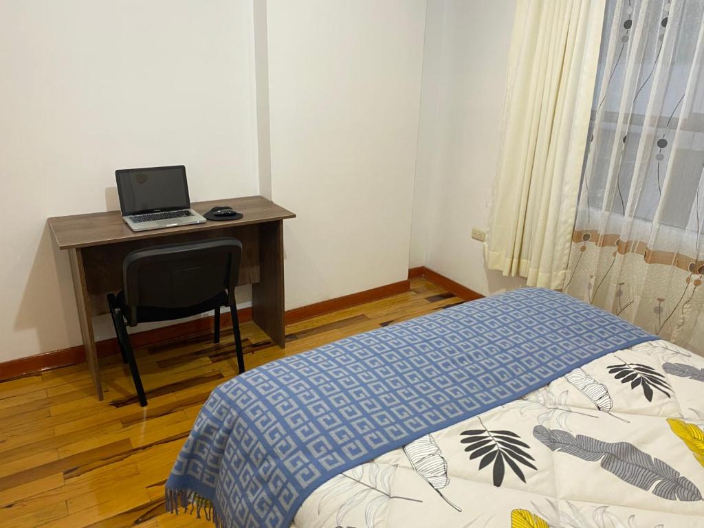 库斯科Hogarcito的一间卧室配有一张床和一张带笔记本电脑的书桌