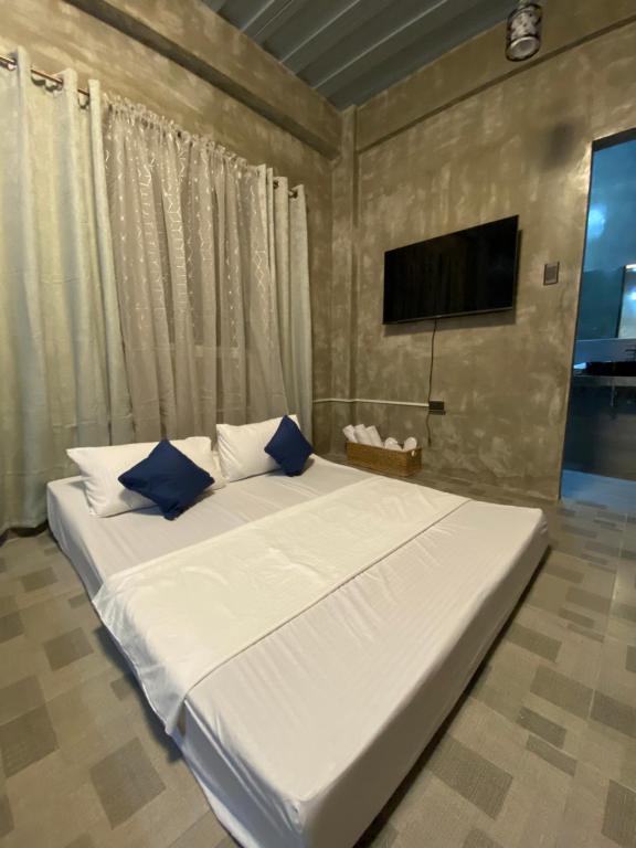 杜马格特Hai Inn的卧室内的一张带蓝色枕头的大型白色床