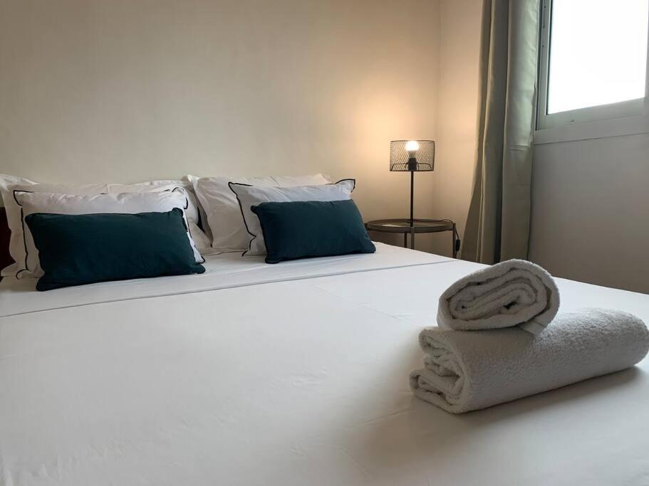 Mamoudzoustudio cocoon perche 119 Mdz的一张带蓝色枕头的白色床和毛巾