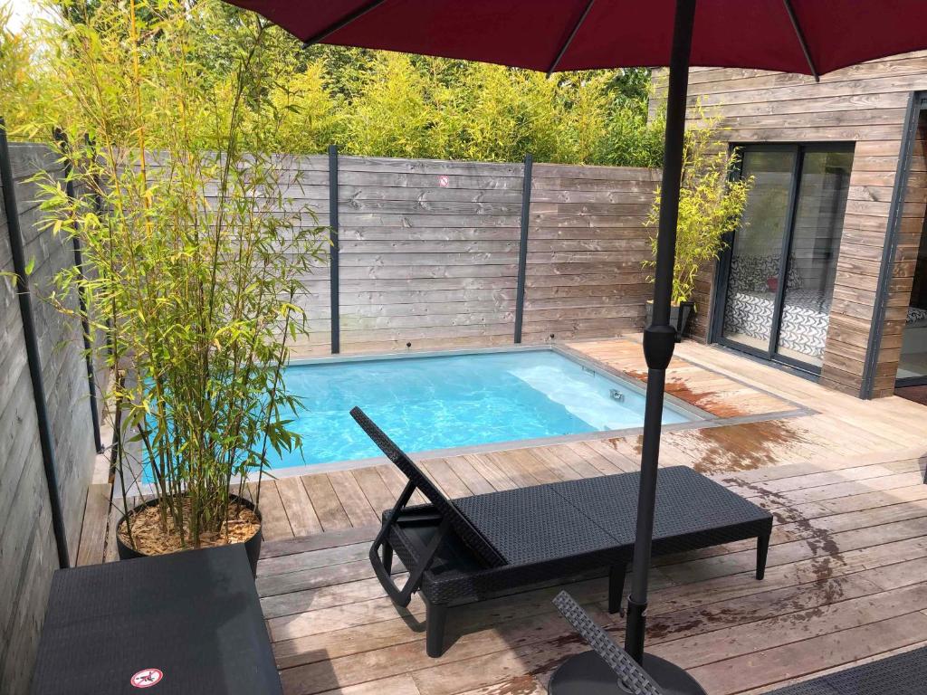 布吕兹Loft privatisé avec spa XXL et piscine chauffée的一个带遮阳伞、桌子和椅子的游泳池