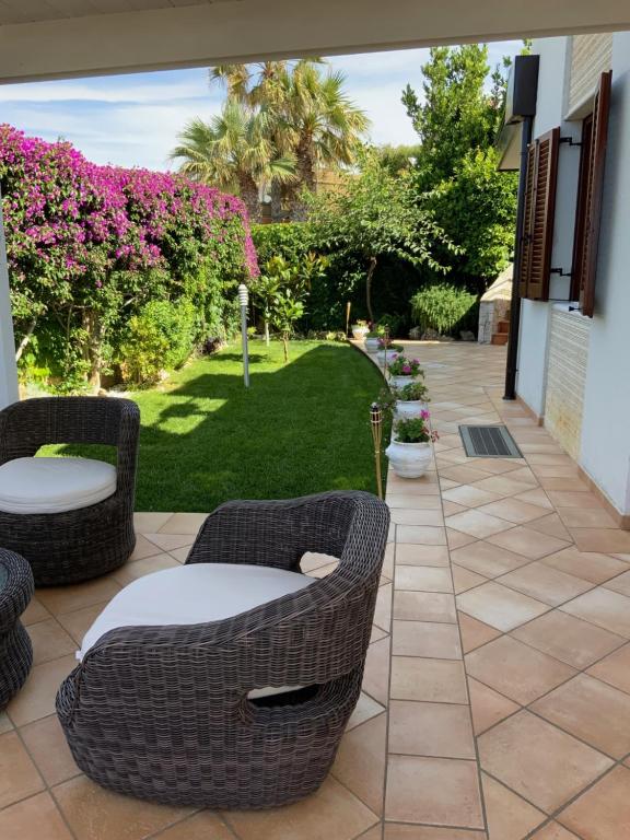 比谢列Villa MarLu的庭院设有藤椅和种有粉红色花卉的草坪。