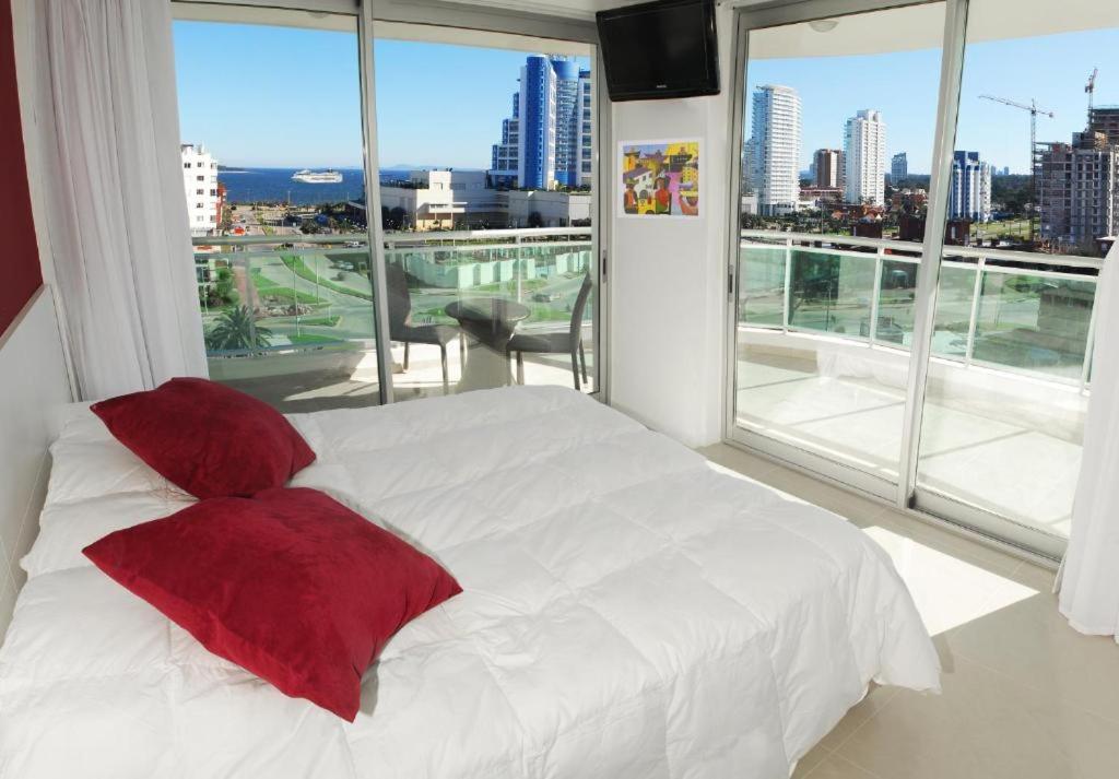 埃斯特角城Categoría, excelente ubicación y full amenities!的卧室配有白色的床和红色枕头