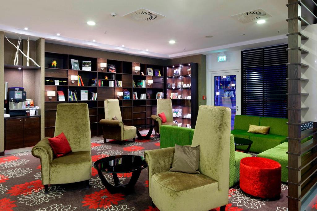 汉诺威翰诺威马斯湖万豪度假酒店的客厅设有绿色椅子和图书馆