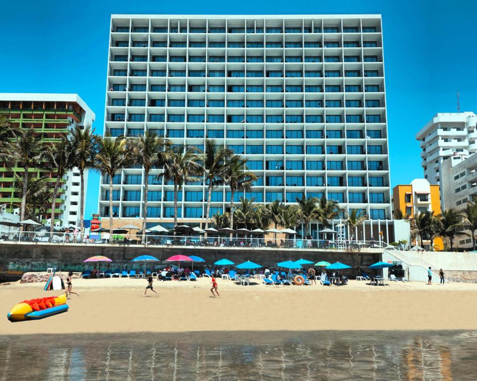 马萨特兰Viaggio Resort Mazatlán的一座拥有大型建筑的海滩,上面有人